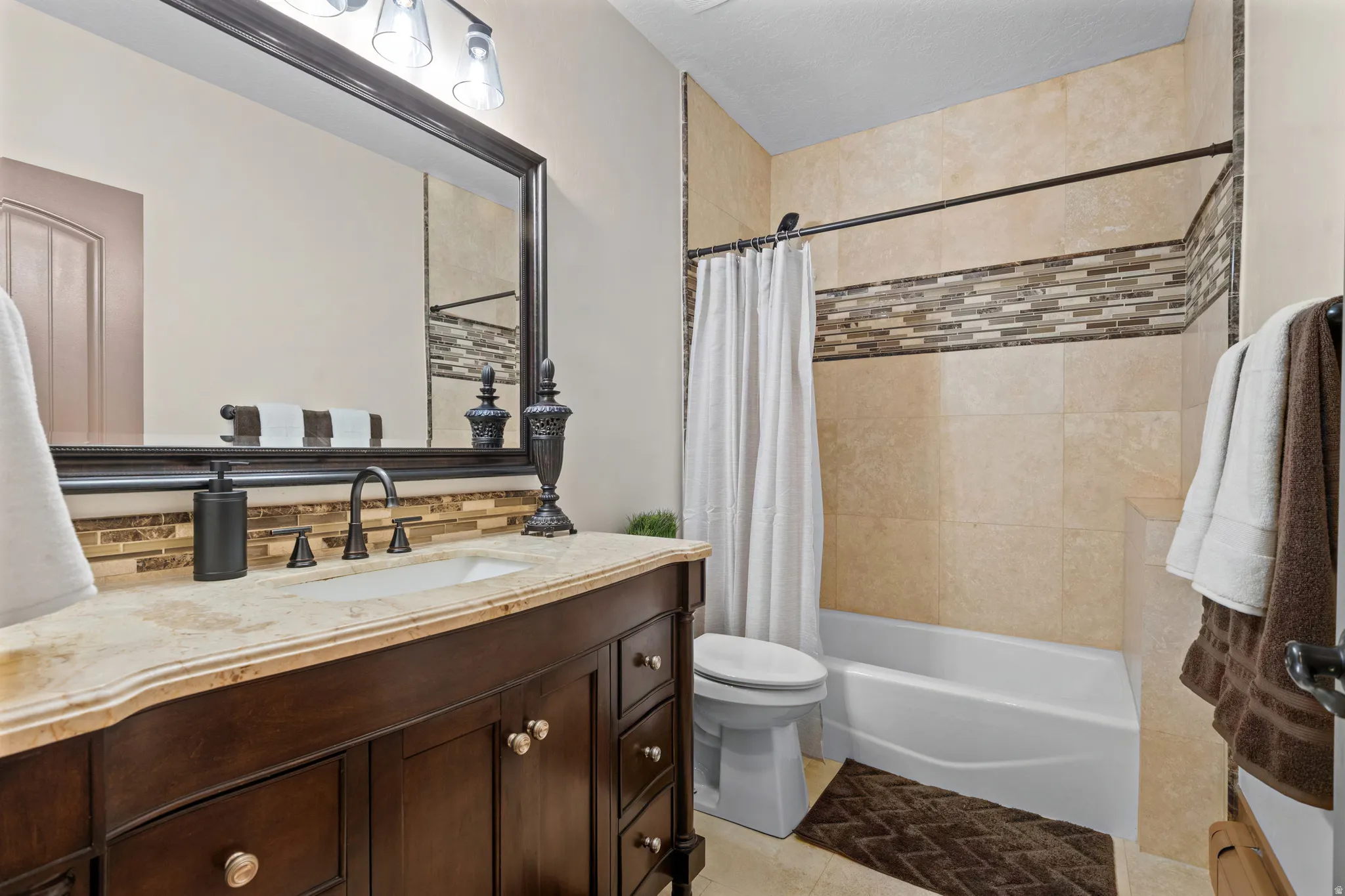 Bathroom featuring a dark wood vanity with a light-colored countertop, an undermount sink, and a dark-framed mirror