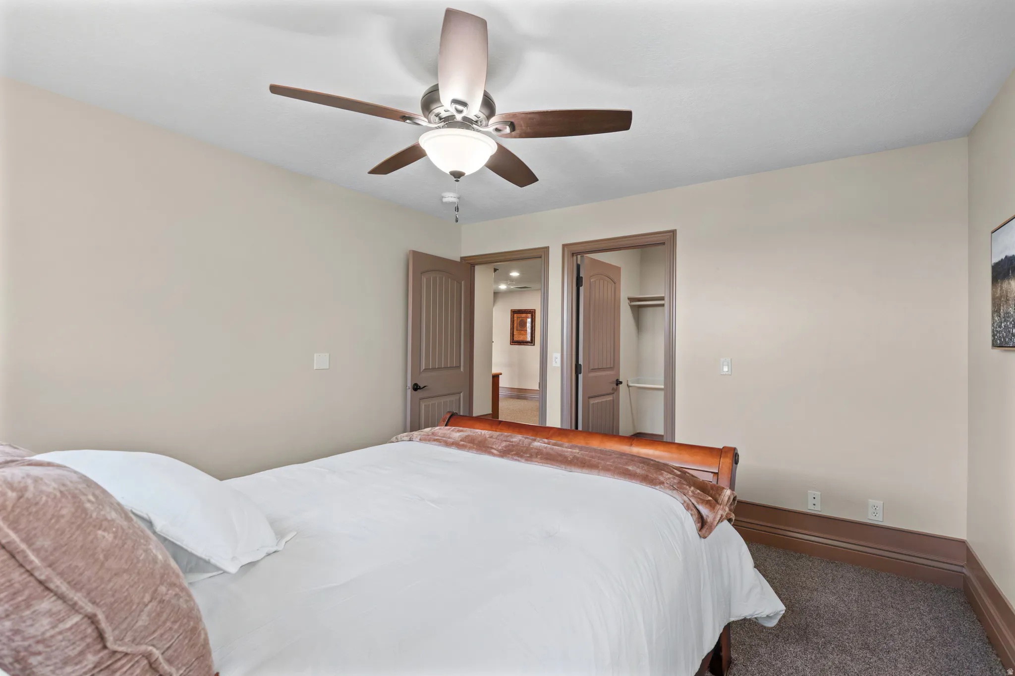 Bedroom featuring neutral-toned walls, dark carpet flooring, and a ceiling fan with integrated lighting