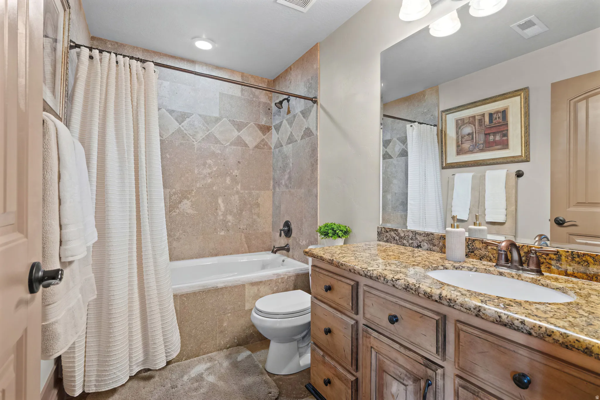Bathroom featuring a spacious vanity with a granite countertop, undermount sink, and bronze faucet