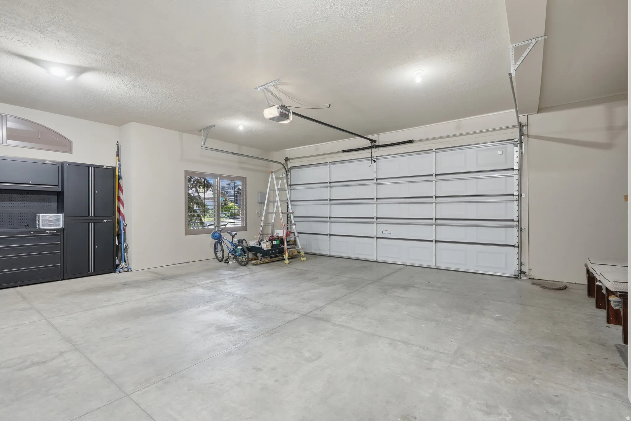 Spacious garage with concrete flooring, overhead lighting, and built-in cabinetry