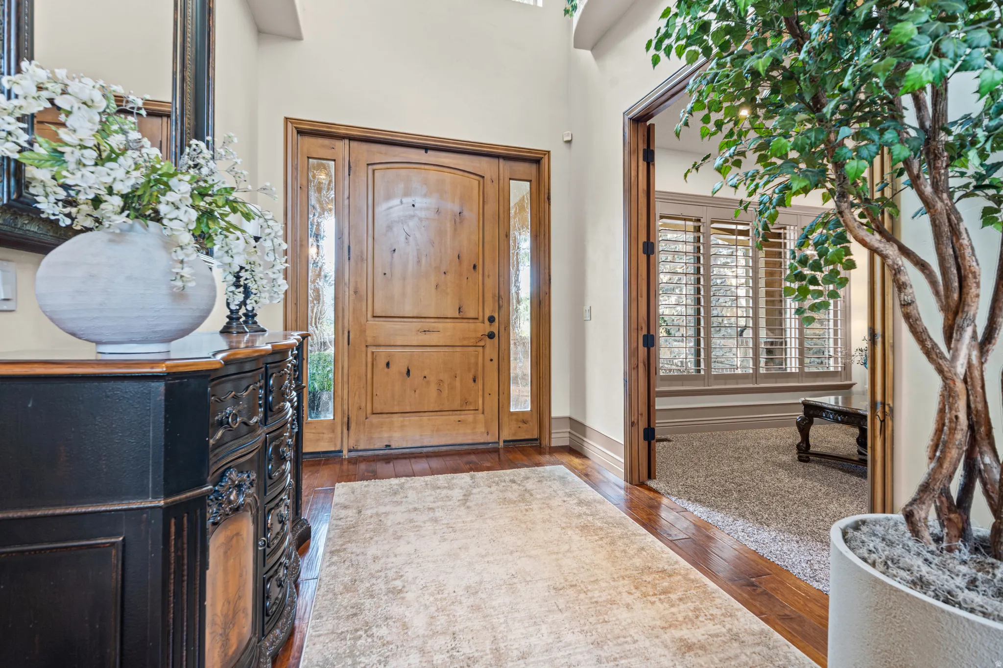 Grand entry featuring a light wood door with sidelight windows, rich wood-finish flooring, and high ceilings