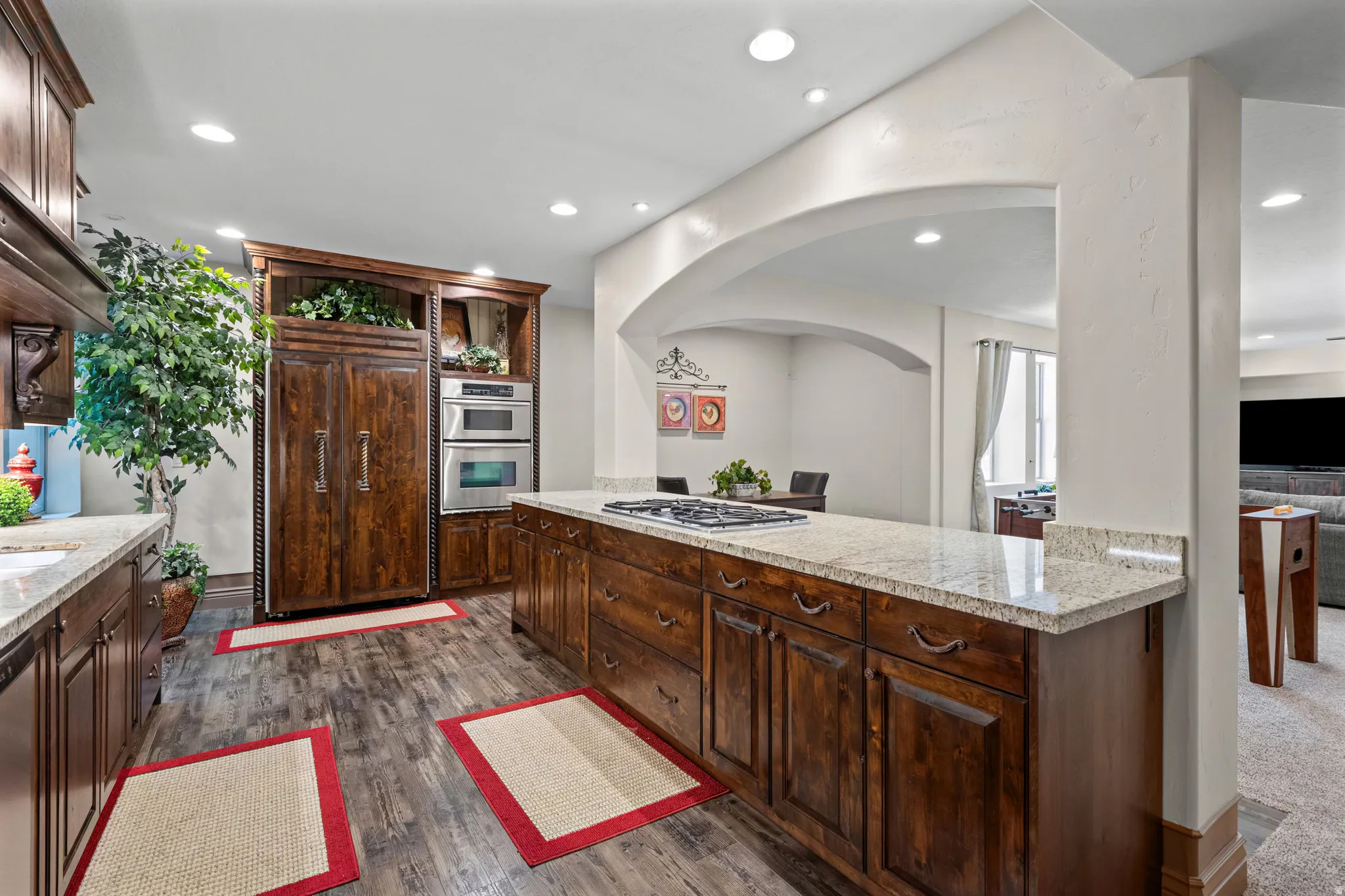 Kitchen featuring extensive wood cabinetry, granite countertops, wood-finish flooring, built-in stainless steel appliances, and recessed lighting