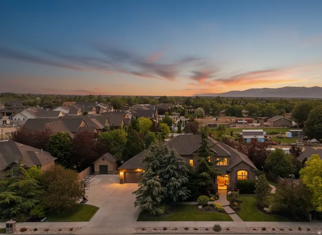 Brick, stone and stucco exterior residence featuring a covered front entry, two-car garage, and mature landscaping