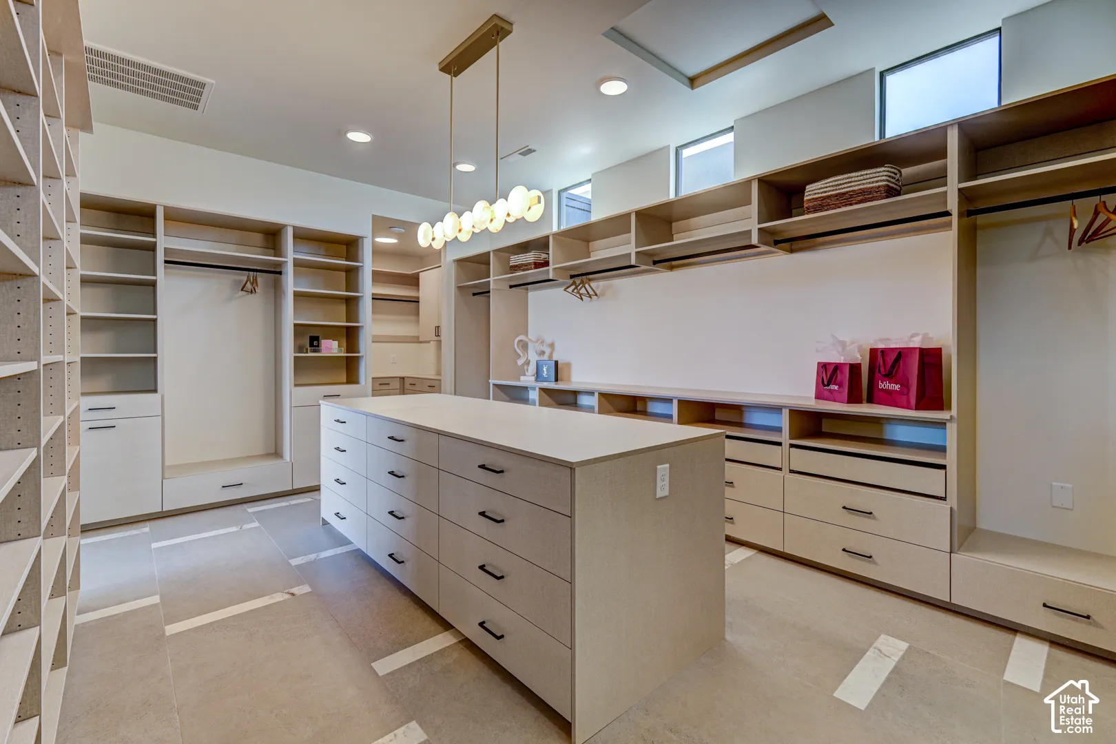 Built-in shelving, integrated drawers, a central island with storage, and a modern ceiling light fixture