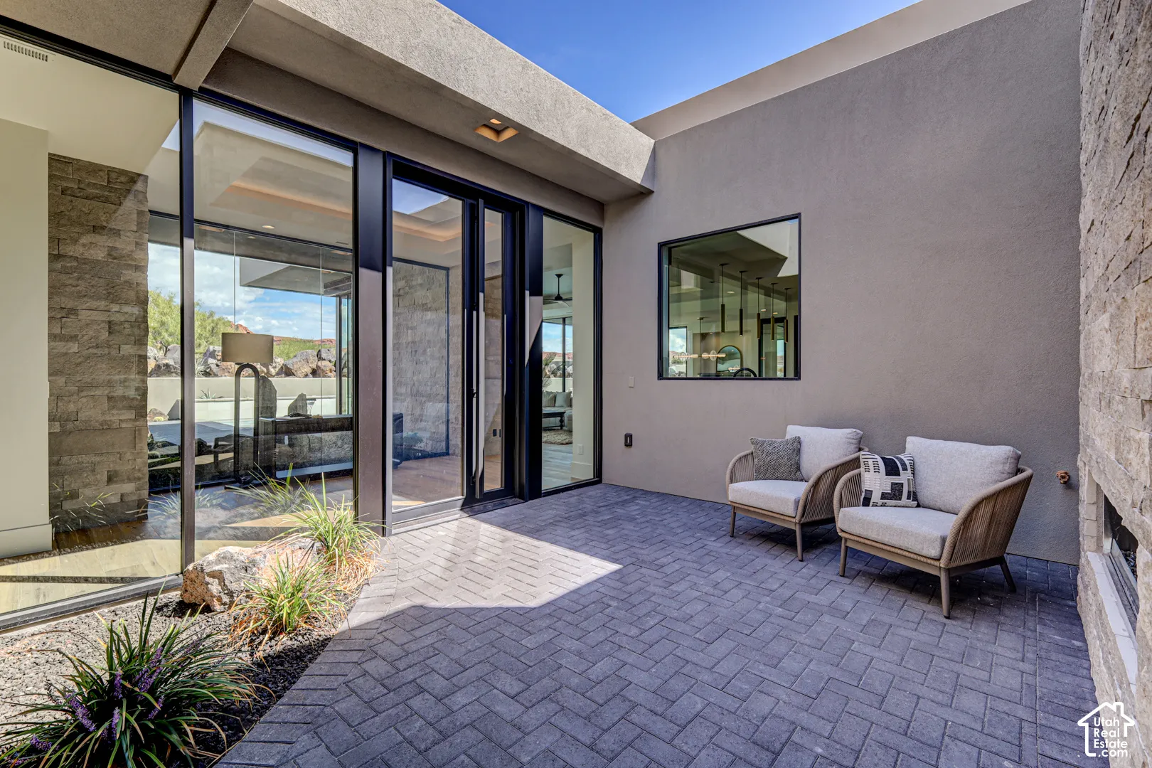 Expansive paved patio with a herringbone pattern, smooth stucco wall, and stacked stone accents