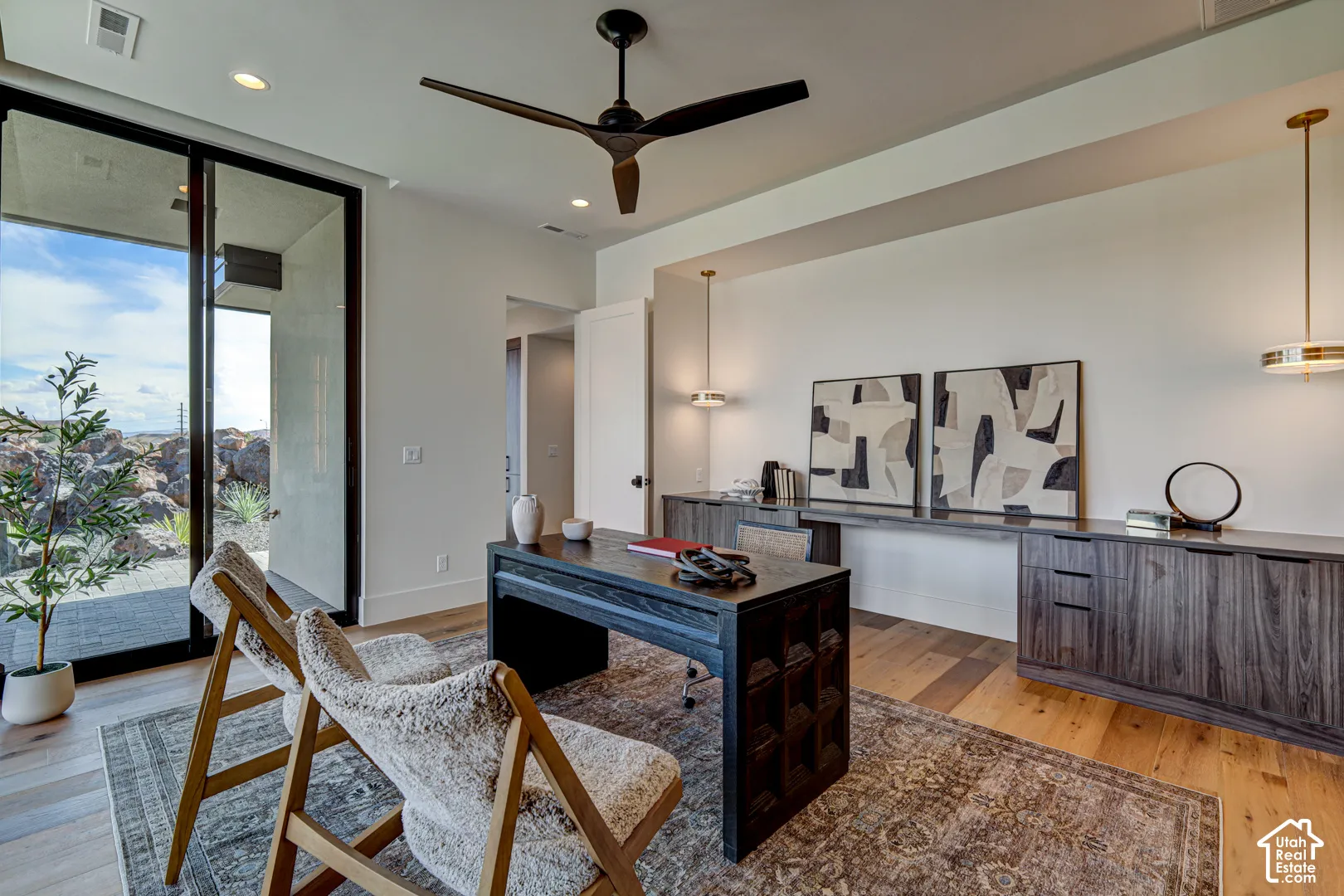 Wood-finish flooring, built-in cabinetry, modern ceiling fan, recessed lighting, and a large sliding glass door