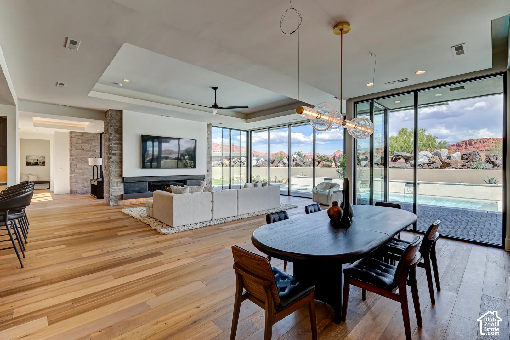 Expansive wood-finish flooring throughout, complemented by a stone-clad fireplace and large glass panel doors