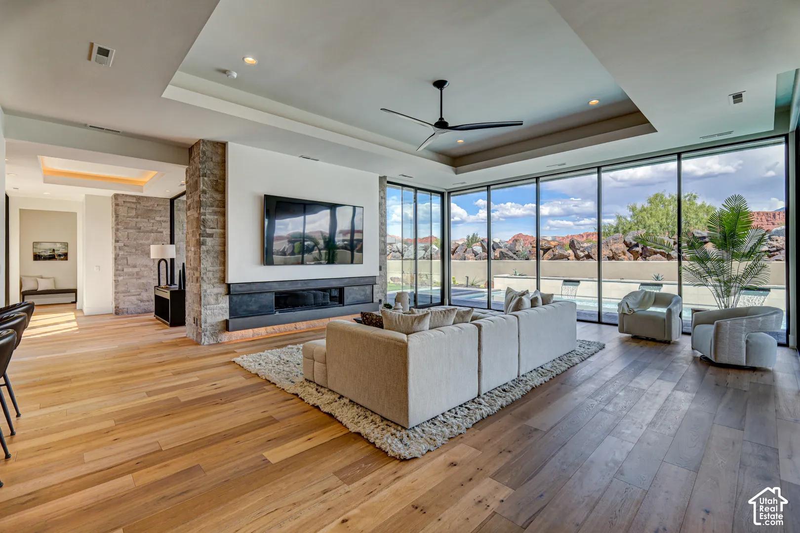 Hardwood-finish flooring, stone accent wall, recessed lighting, linear fireplace, and floor-to-ceiling windows