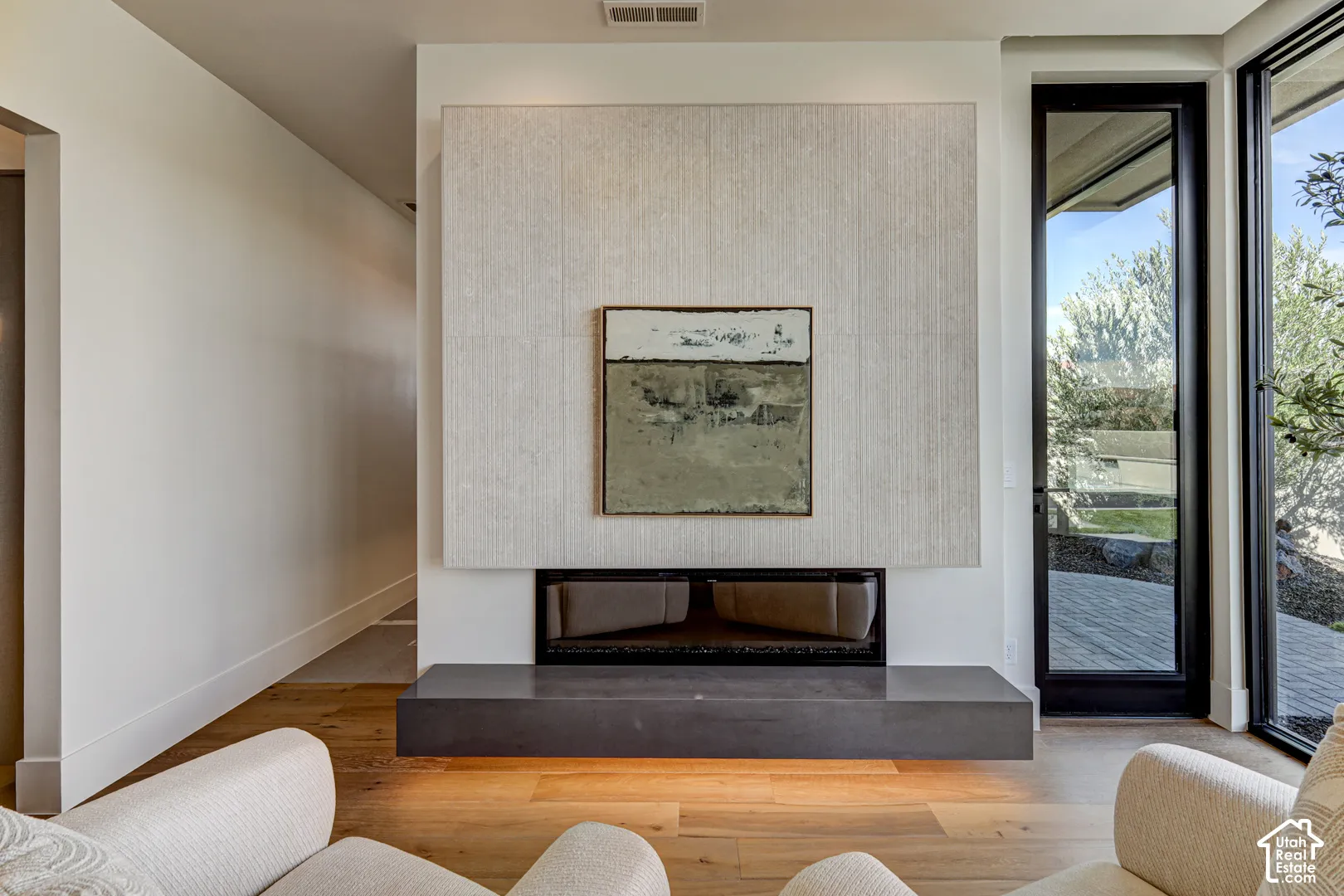Modern fireplace with a textured surround, a dark hearth, and light wood-finish flooring