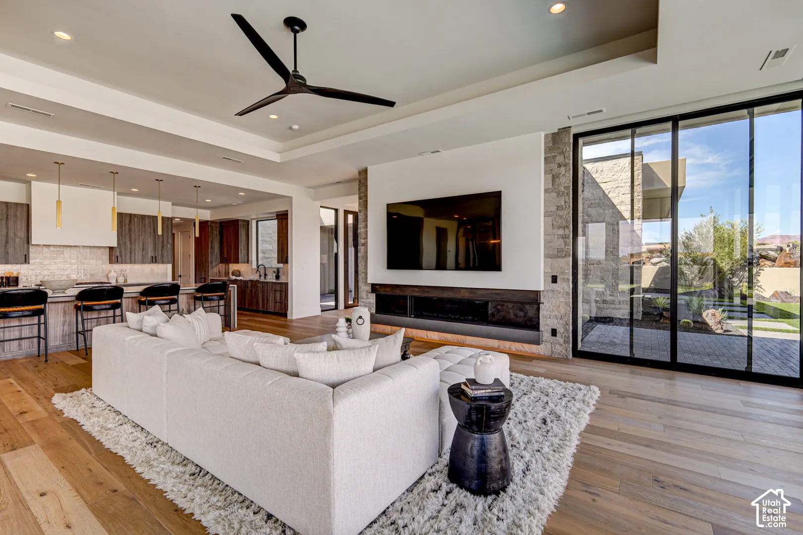Expansive open-concept living area featuring wood-finish flooring, a contemporary fireplace, and a large sliding glass door