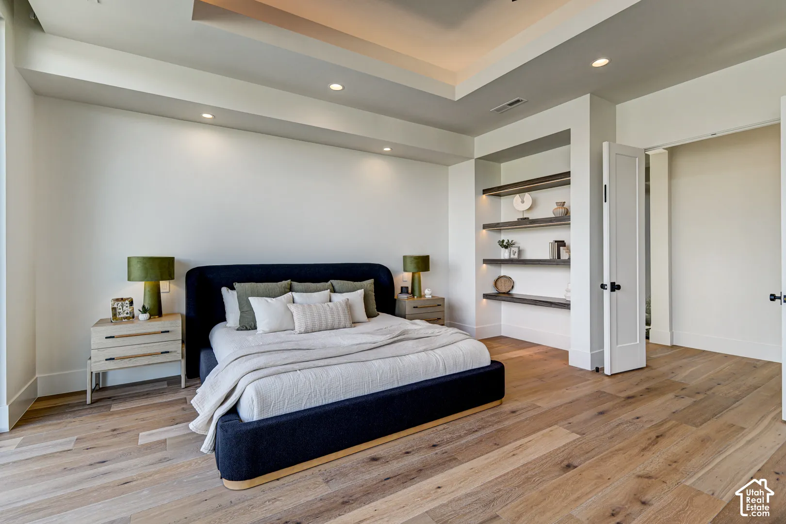 Wide plank wood-finish flooring complemented by a tray ceiling with recessed lighting