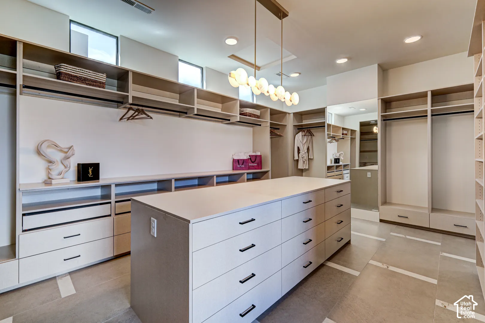 Spacious custom closet featuring an expansive central island with drawers, integrated shelving, and multiple hanging rods
