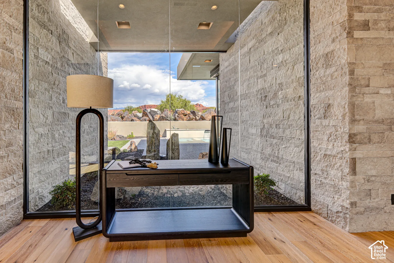 Floor-to-ceiling windows, natural stone wall cladding, wood-finish flooring, and recessed ceiling lighting