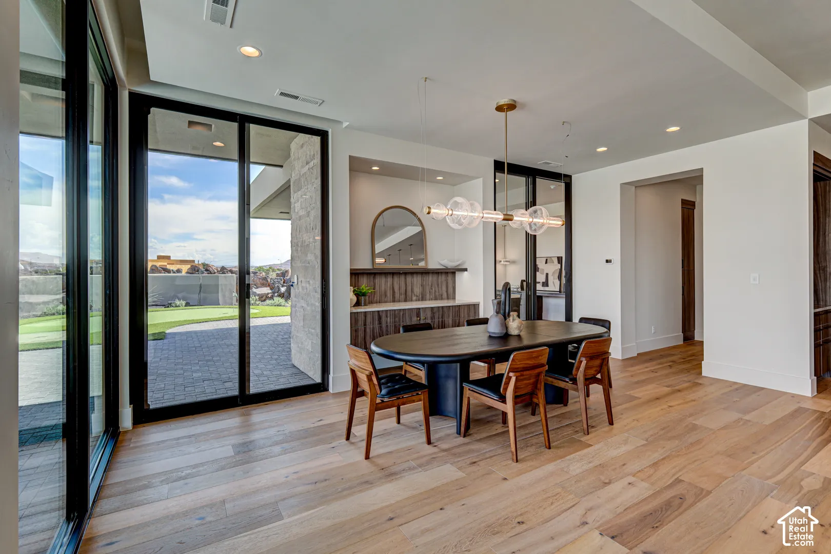Light wood-finish flooring, recessed lighting, expansive glass doors, and a built-in buffet with a wood-finish countertop
