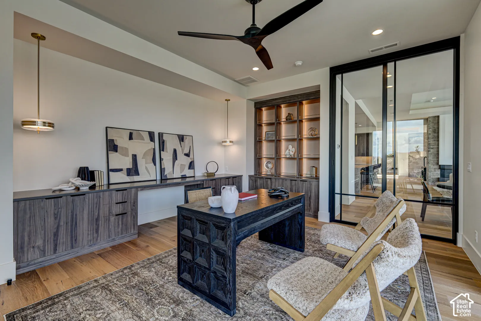 Hardwood flooring, built-in cabinetry with integrated lighting, modern ceiling fan, and sliding glass wall panels