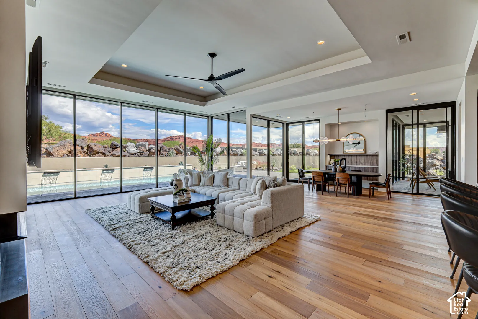 Expansive living area with wood-finish flooring, recessed lighting, and a modern ceiling fan