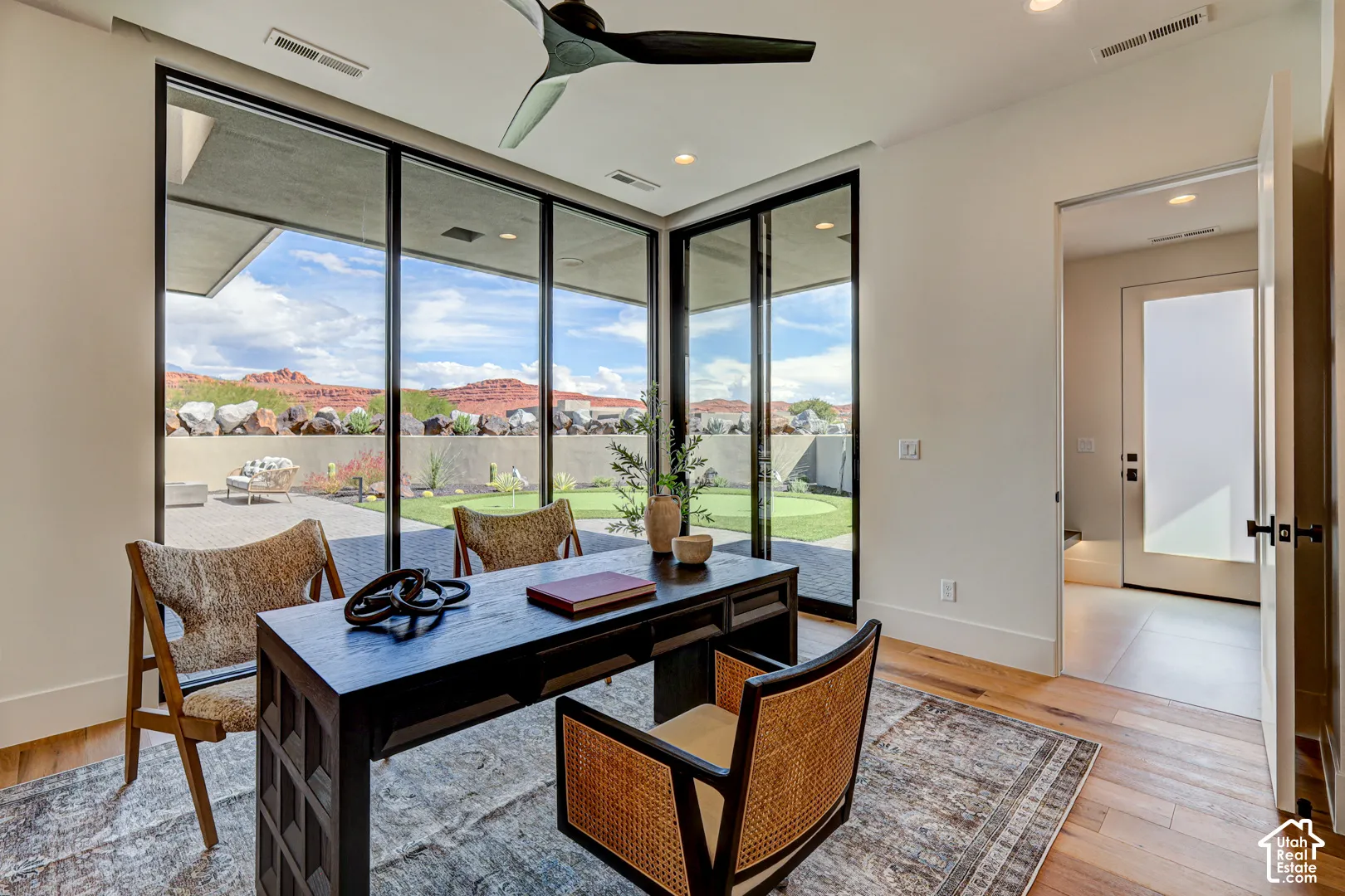 Expansive glass wall with black framing, wood-finish flooring, recessed lighting, and a modern ceiling fan