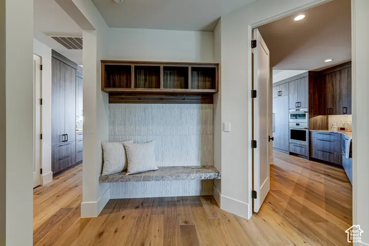 Hardwood flooring throughout, built-in mudroom bench with stone top, integrated wall cubbies, and a textured wall panel