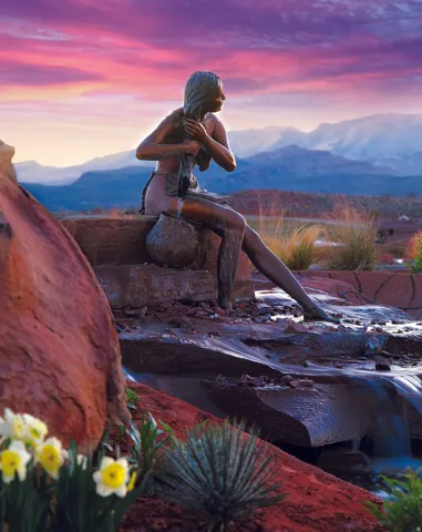 Sculpted bronze figure at water feature with rock landscaping