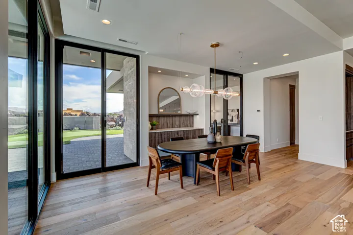 Light wood-finish flooring, recessed lighting, expansive glass doors, and a built-in buffet with a wood-finish countertop
