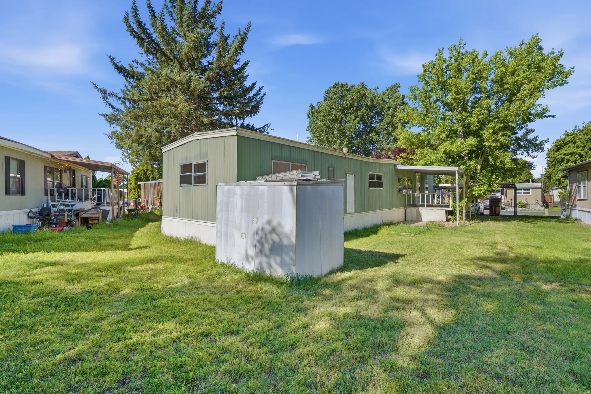 Expansive green space featuring established trees and a storage shed