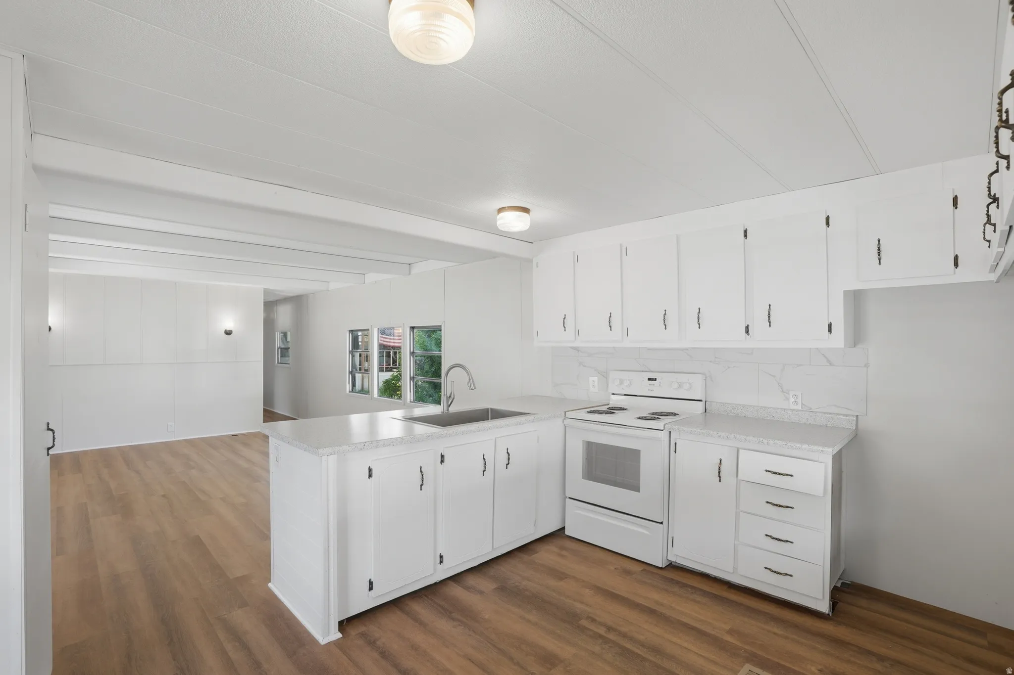 Kitchen featuring white cabinetry, a stainless steel sink, white electric range, and laminate countertops
