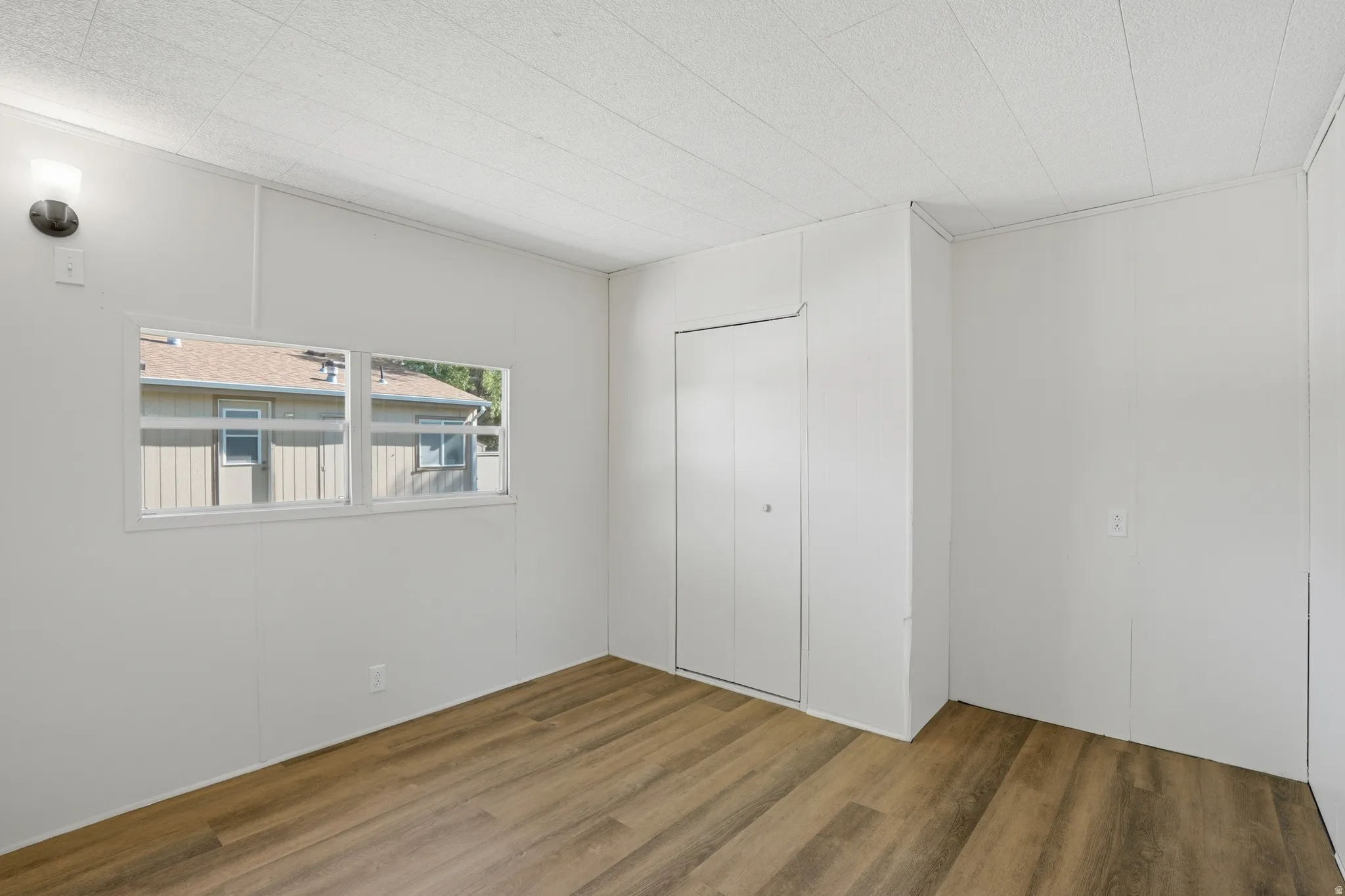 Room featuring wood-finish flooring, light panel walls, and a white ceiling