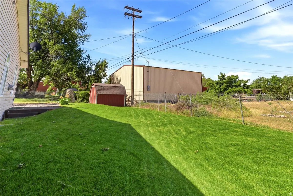 Expansive green lawn with a red storage shed, mature trees, and a wooden deck