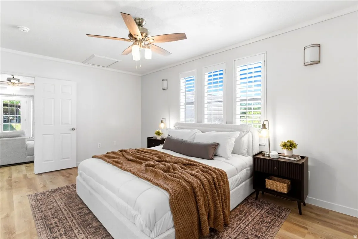 Bedroom featuring wood-finish flooring, white walls, and a ceiling fan with integrated lighting