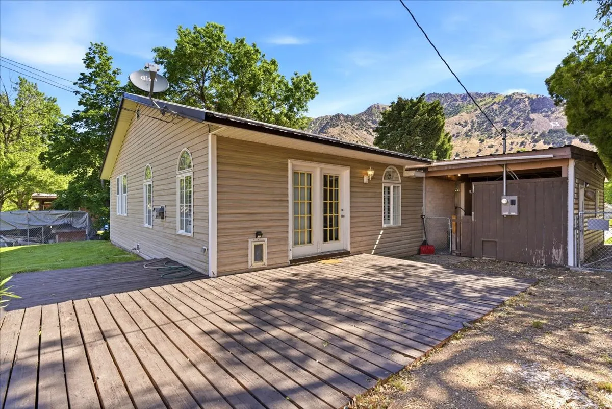 Rear exterior featuring light-toned horizontal siding and a spacious wooden deck