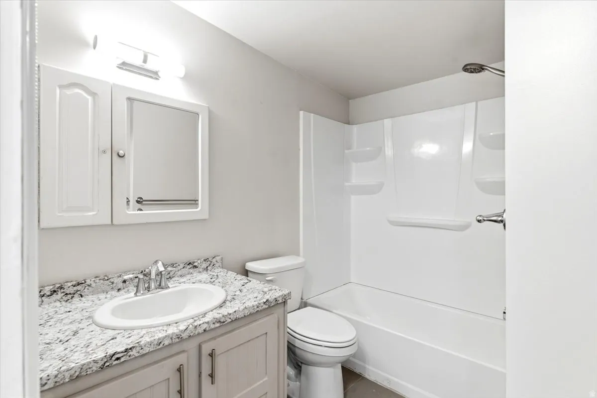 Bathroom featuring a white vanity with a speckled countertop, undermount sink, and chrome faucet