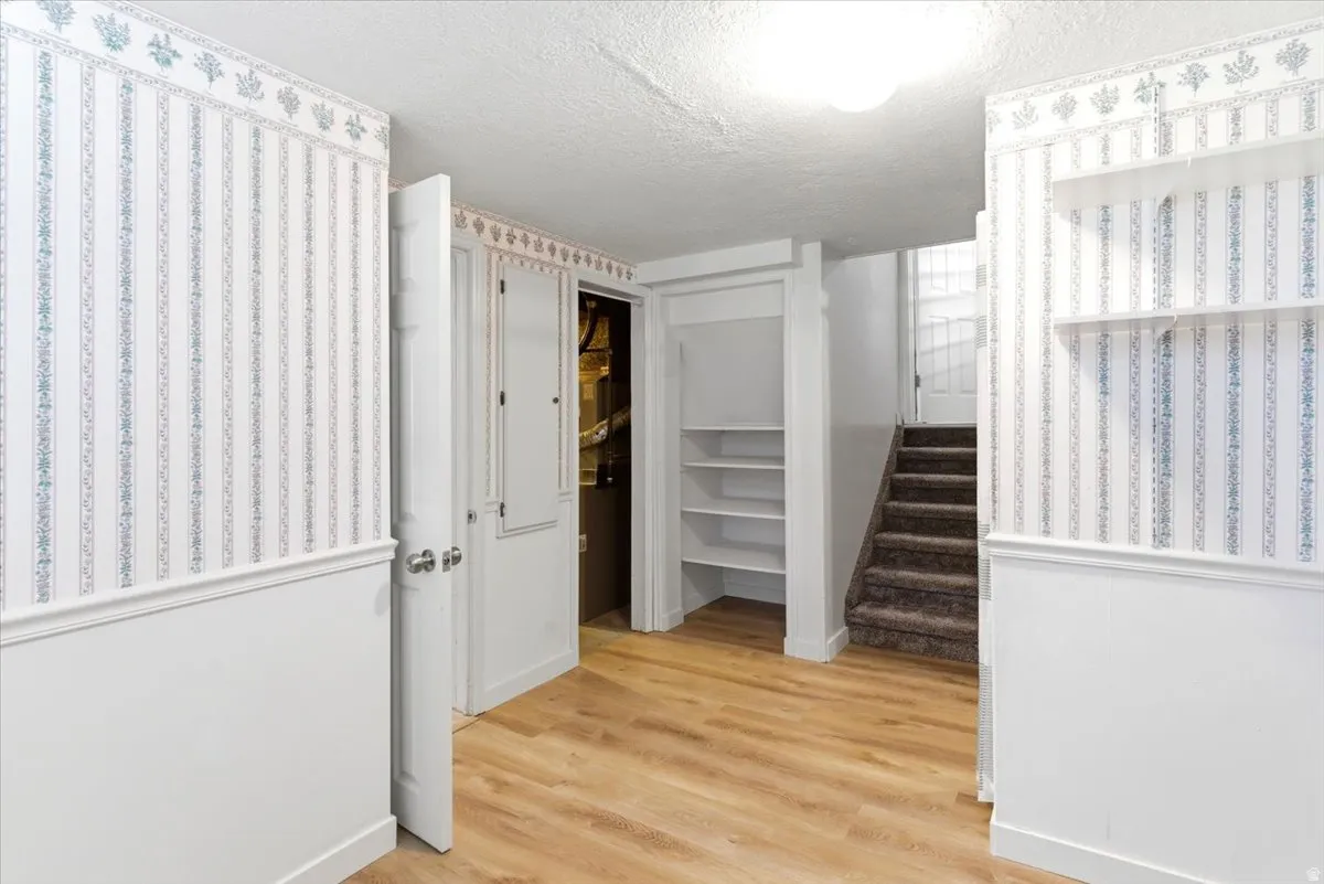 Wood-finish flooring with white wainscoting and striped wallpaper