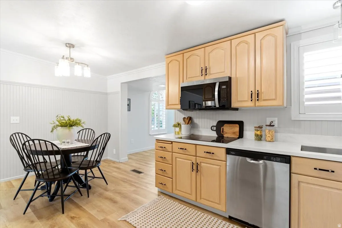 Kitchen featuring light wood cabinetry, stainless steel appliances, a built-in microwave, light countertops, and a white tile backsplash