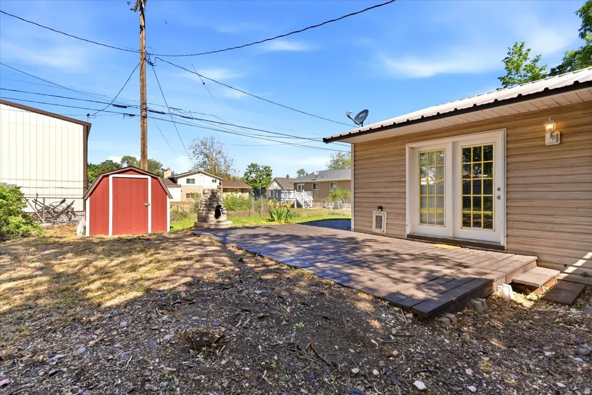 Rear exterior featuring a wood-finish deck, double French doors, and an outdoor light fixture