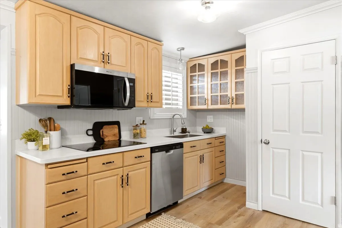 Kitchen featuring light wood cabinetry with brushed nickel hardware, white countertops, and a white beadboard backsplash