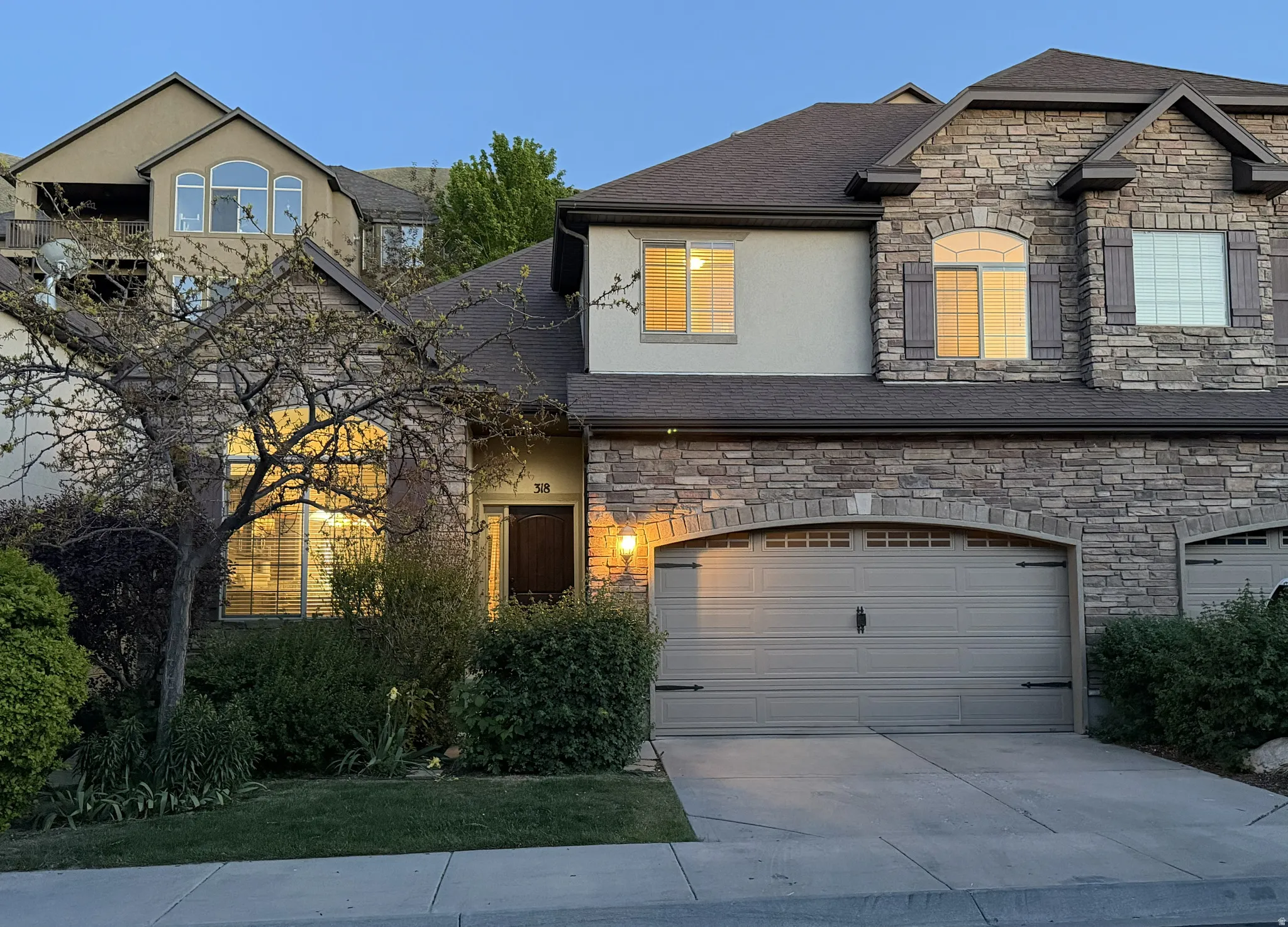 Stone and stucco exterior featuring a two-car garage with an arched stone surround