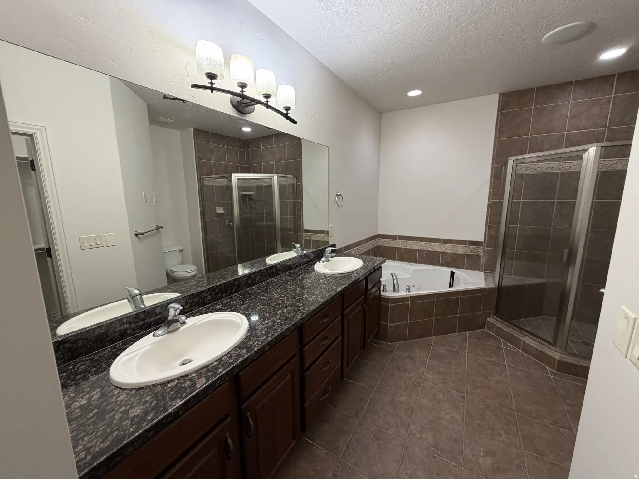 Bathroom featuring a dual vanity with dark wood-finish cabinetry and stone countertops