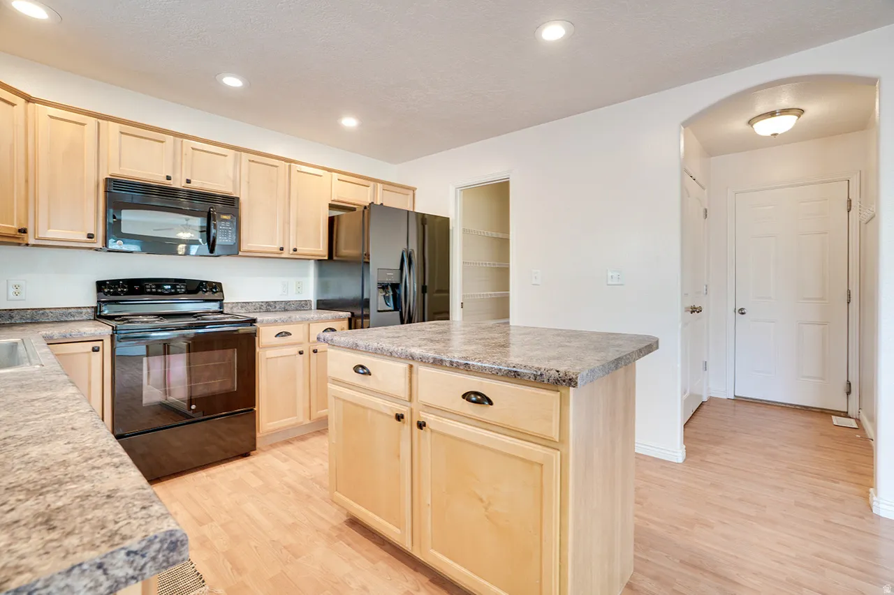 Kitchen featuring wood-finish flooring, light wood cabinetry, stone-look countertops, and recessed lighting