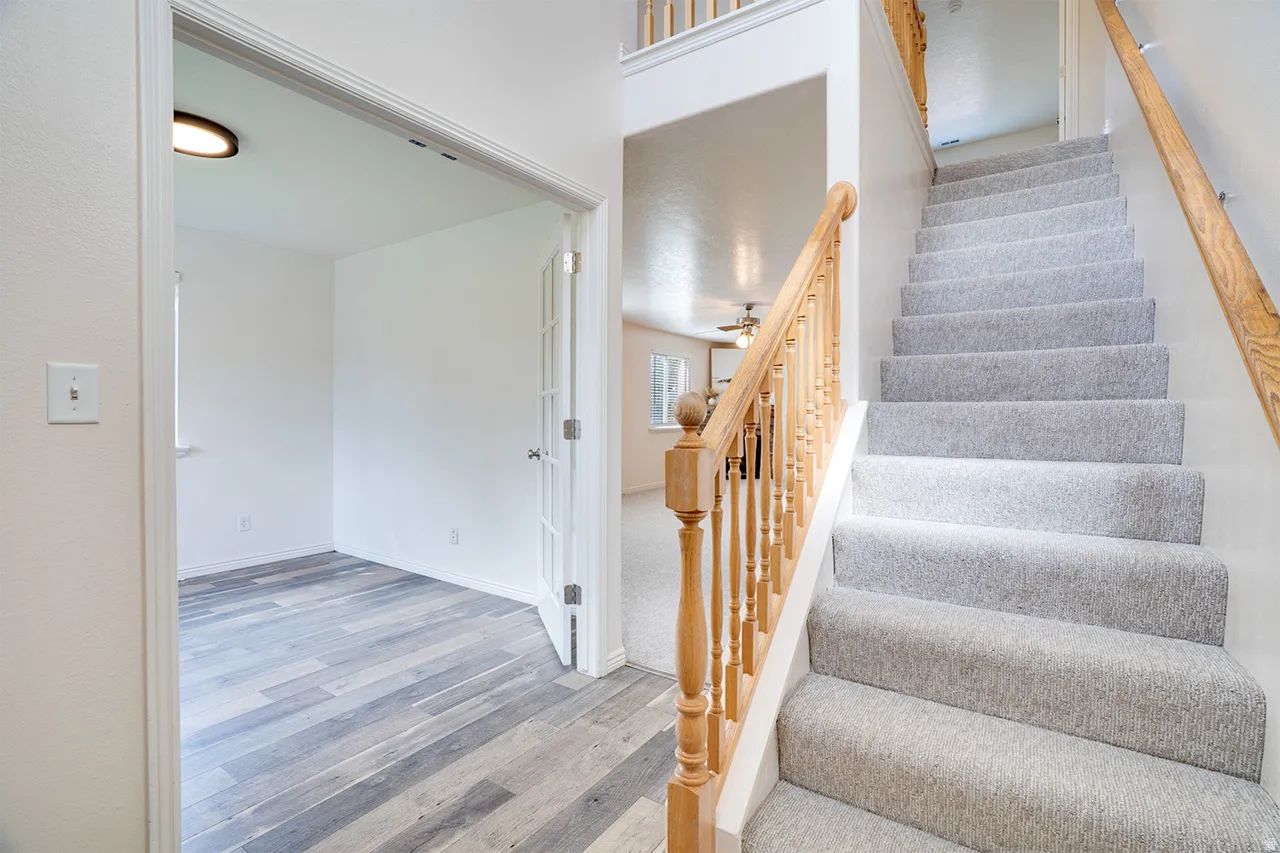 Carpeted staircase with natural wood handrail and spindles