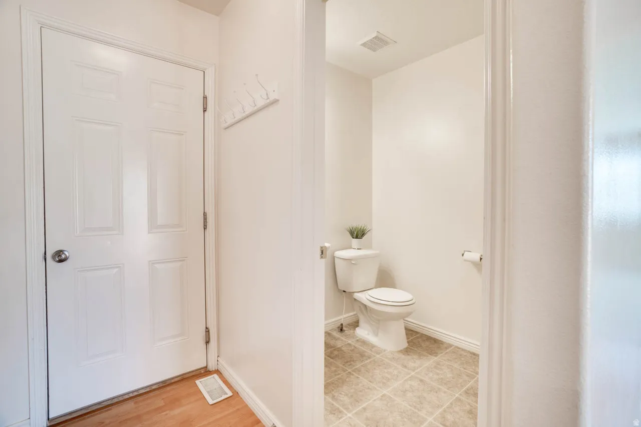 Powder room featuring a white toilet, tile flooring, and light-toned walls