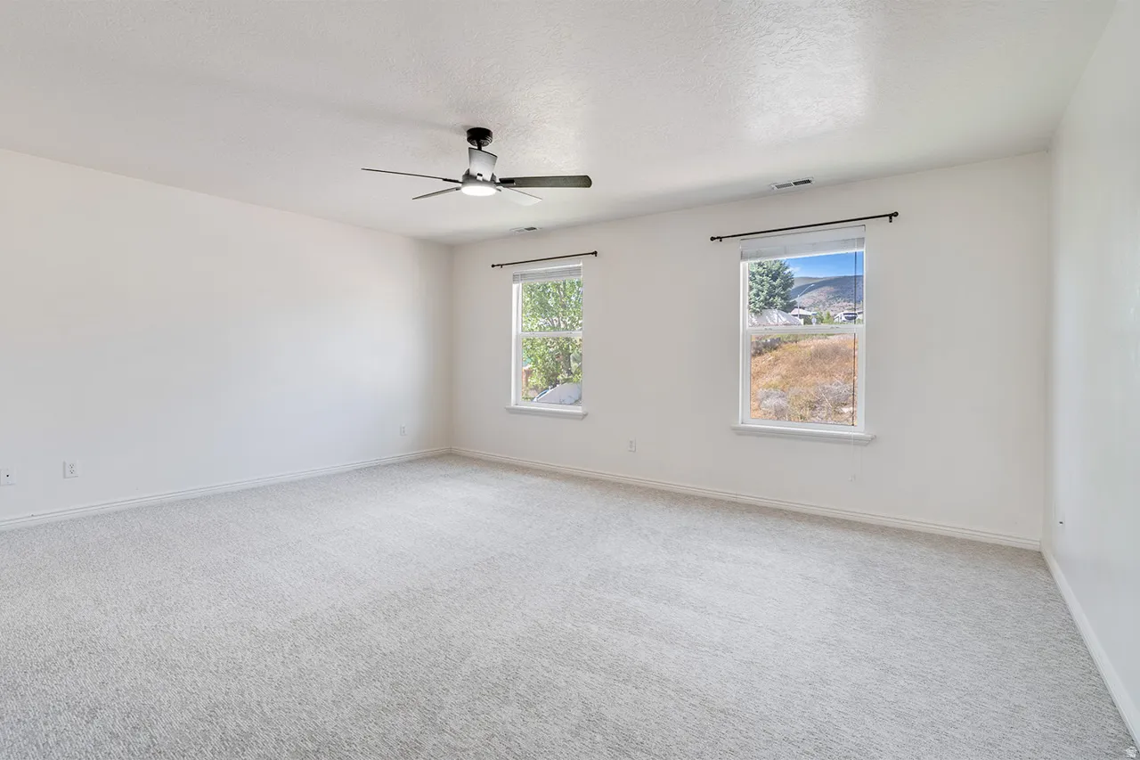 Spacious room featuring light-colored carpeting and white walls