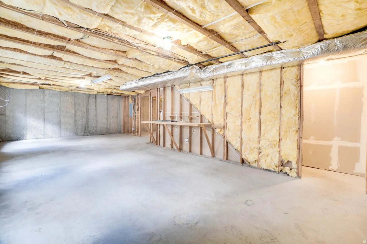 Unfinished basement featuring exposed insulation, concrete flooring, concrete foundation walls, and framed interior walls