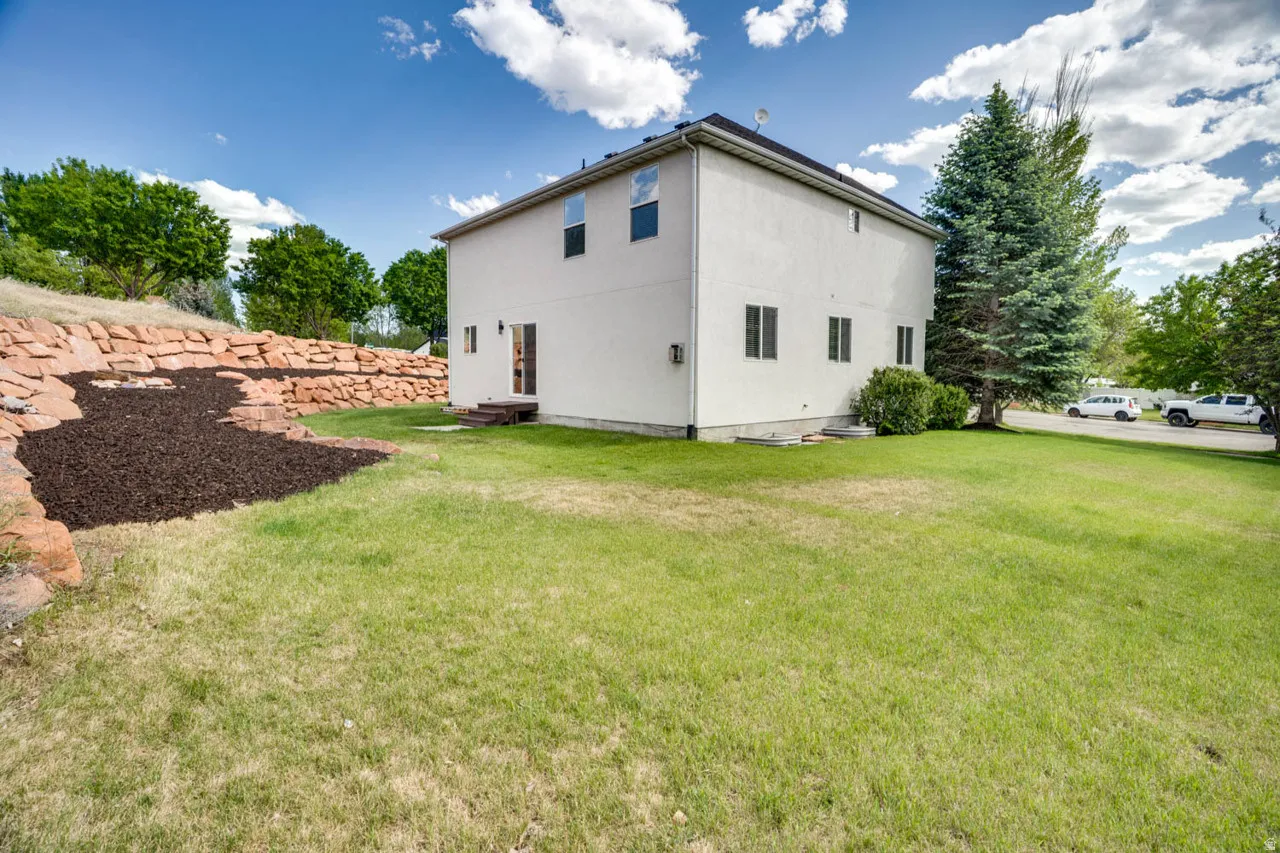 Expansive grassy yard with a built-in stone retaining wall and an adjacent mulched area