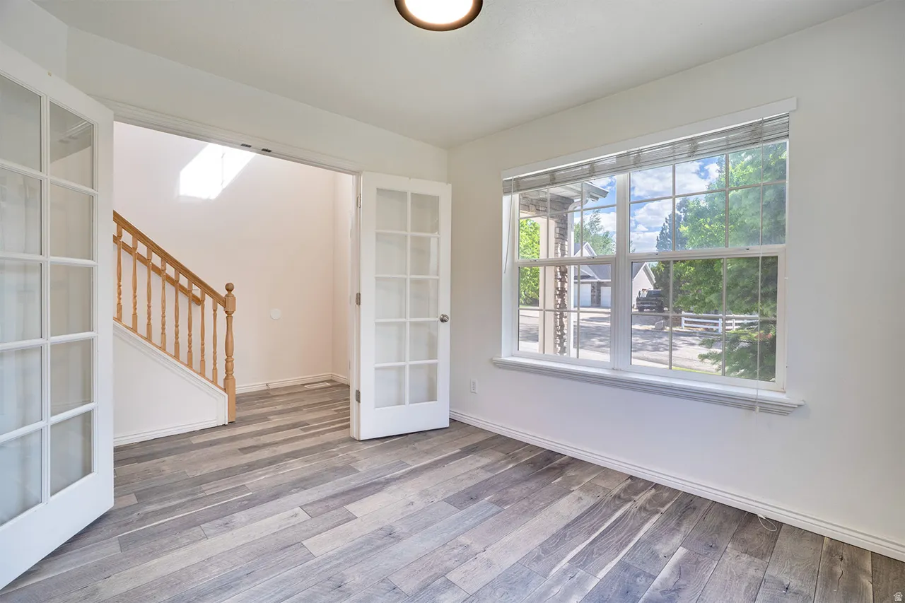 Spacious room featuring wood-finish flooring and white walls