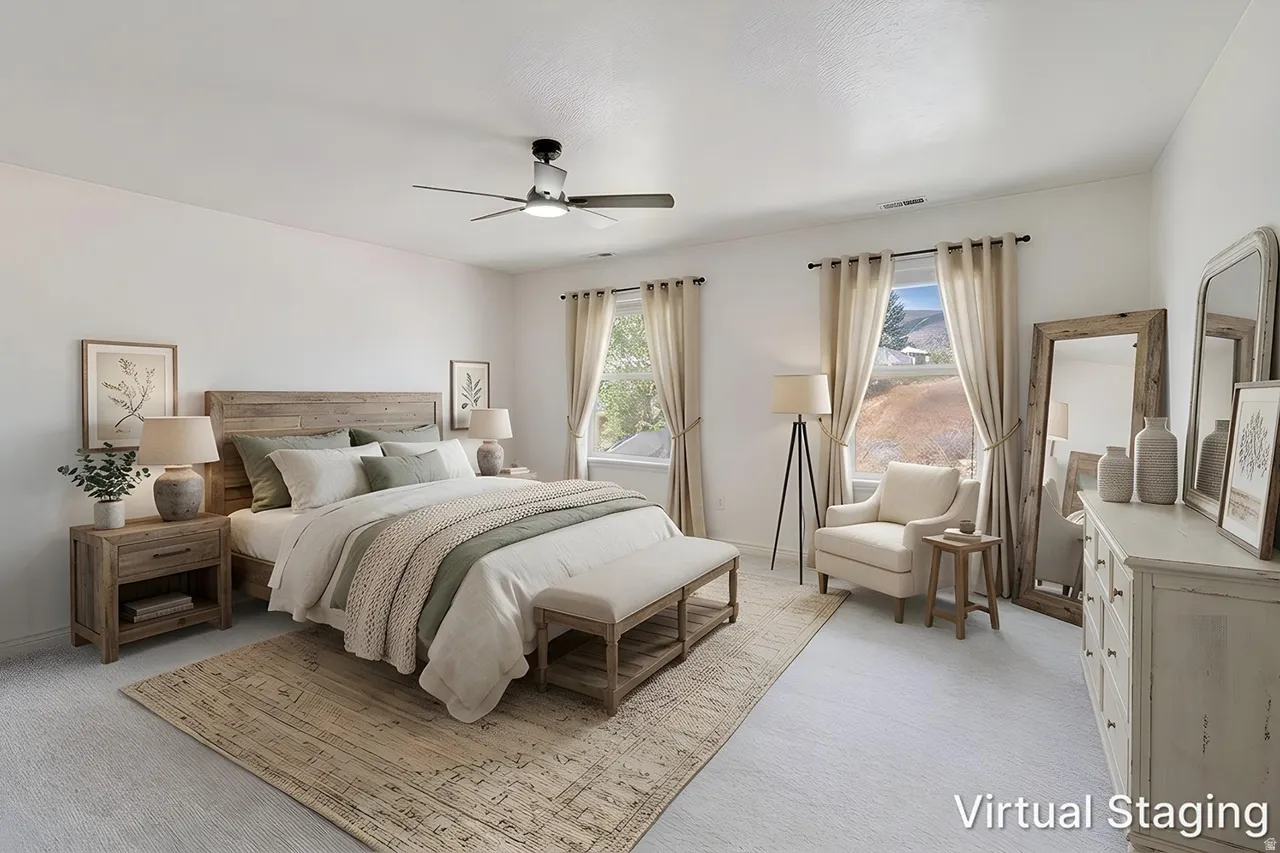 Spacious bedroom featuring light-colored carpeting, two windows with drapery, and a ceiling fan