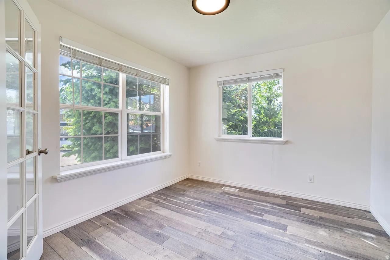 Room featuring wood-finish flooring, white walls, and a multi-pane window with white trim