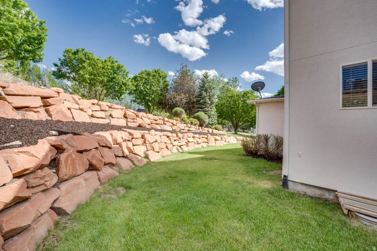 Landscaped terraced backyard featuring natural stone retaining walls and green lawn