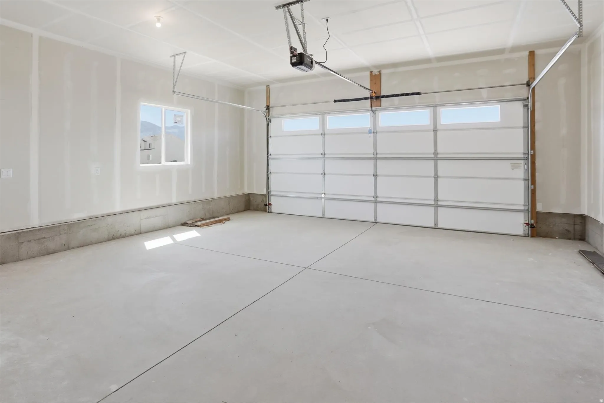 Spacious garage featuring a concrete floor, an overhead garage door with integrated windows, and a single window providing natural light