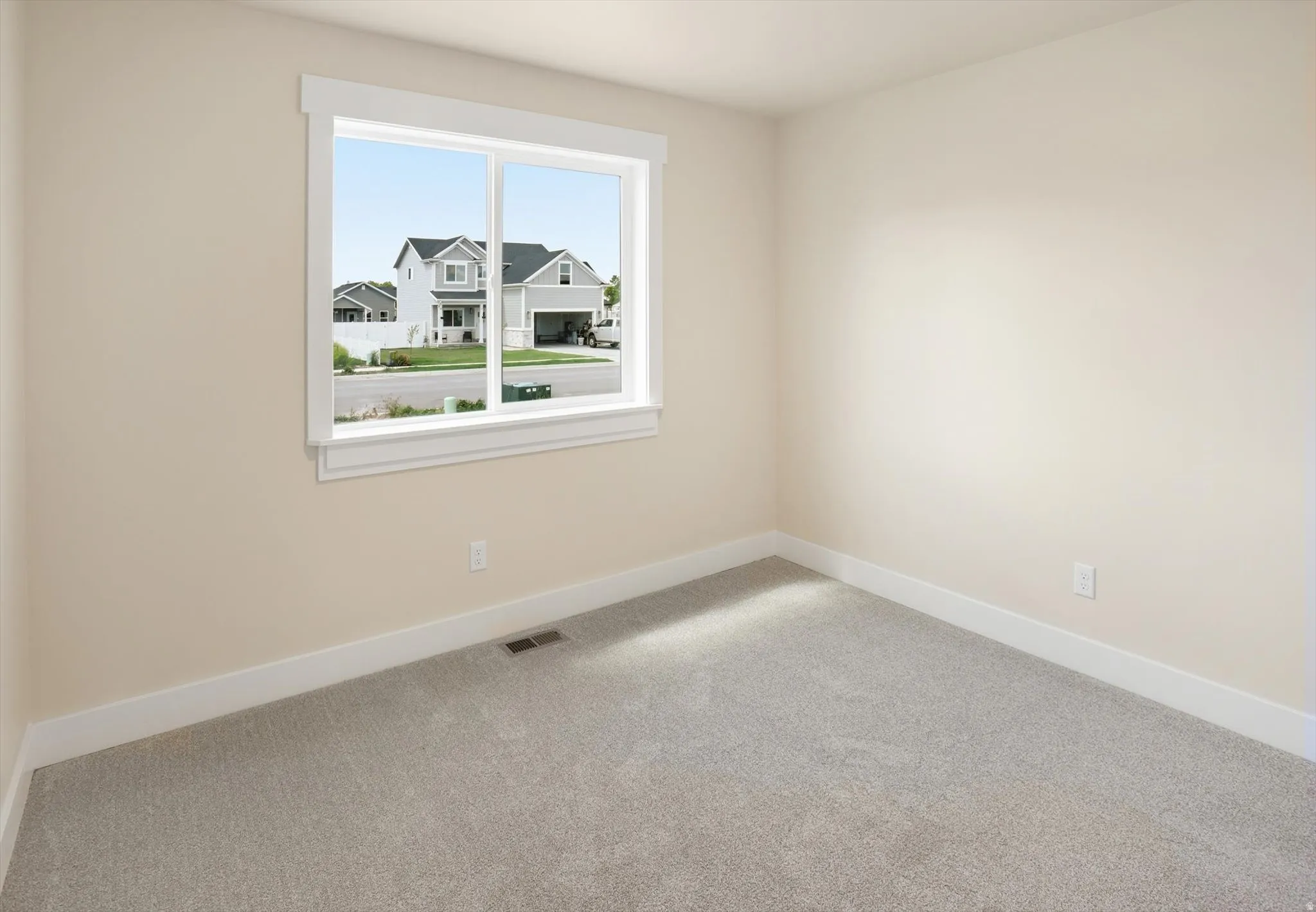 Windowed interior room featuring light gray carpet, neutral painted walls, and white trim molding
