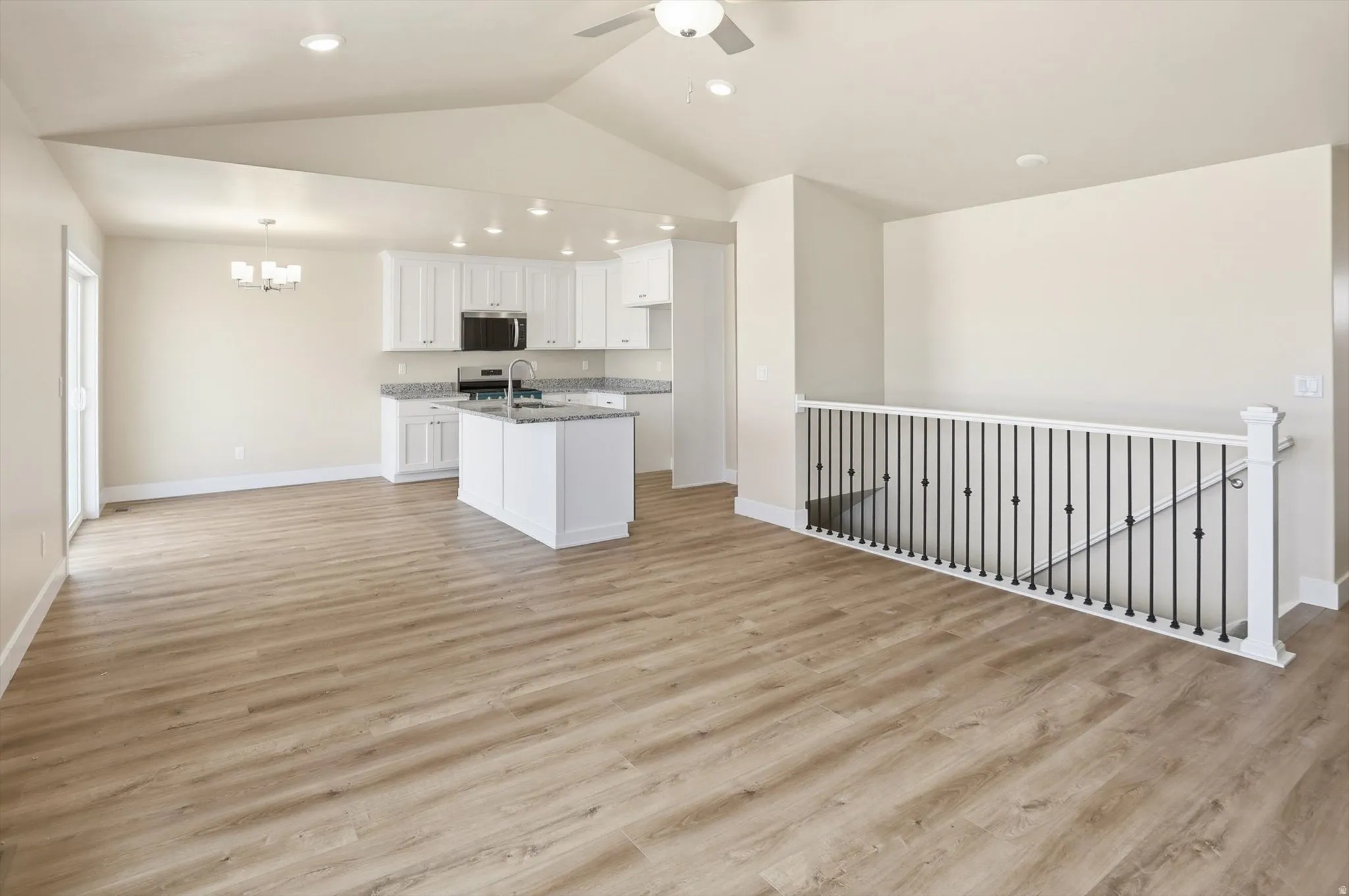 Spacious living area featuring wood-finish flooring, a vaulted ceiling, and recessed lighting